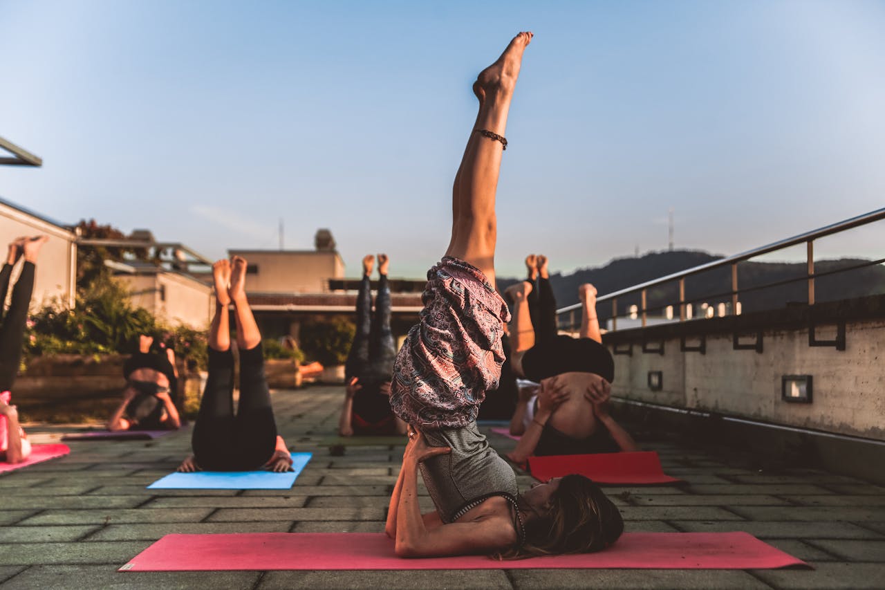services-03 People practicing yoga on mats outdoors during sunset, focusing on wellness.
